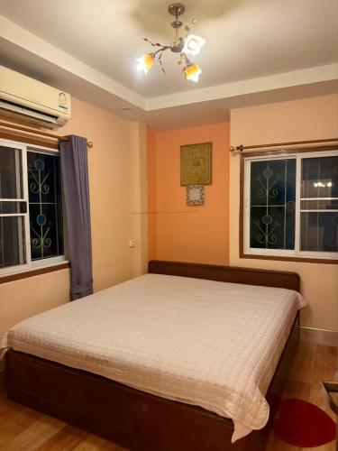 a bedroom with a bed and two windows at Buriram Cozy Home in Buriram