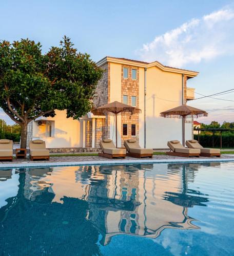 a pool with chairs and umbrellas in front of a building at Riverside Apartments in Ulcinj