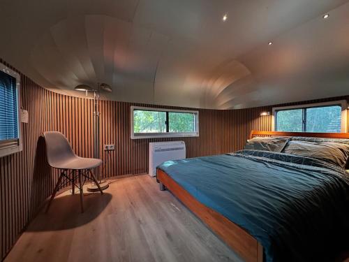 a bedroom with a bed and a chair in it at Tin Can Town Oirschot in Oirschot