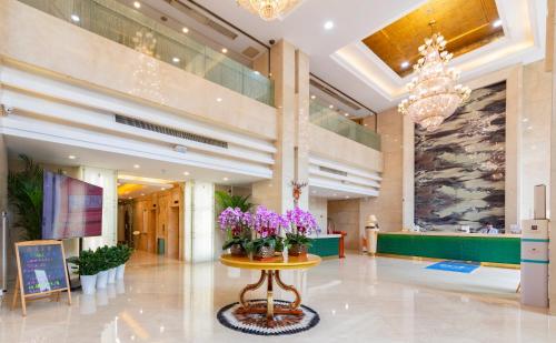 a lobby with a table with flowers on it at Shanghai Metropark Jichen Hotel in Shanghai