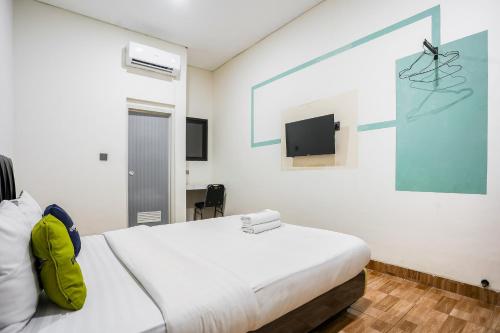a bedroom with a bed and a tv on the wall at Urbanview Hotel Aloevera Pontianak by RedDoorz in Pontianak