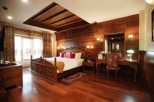 a bedroom with a large bed and a desk and a chair at JC Residency Madurai in Madurai