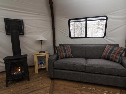 a living room with a couch and a stove at Chalets Lanaudière - Yourtes in Rawdon