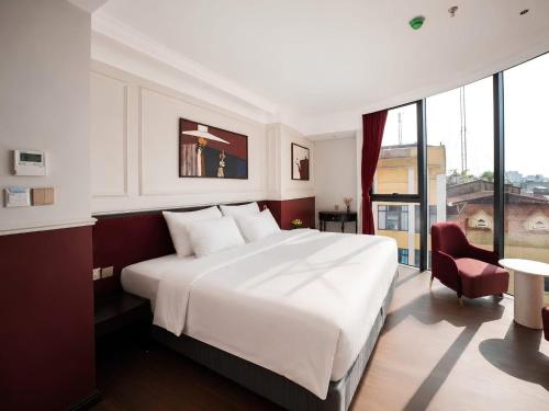 a bedroom with a large white bed and a red chair at La Passion Elegance Hotel & Spa in Hanoi