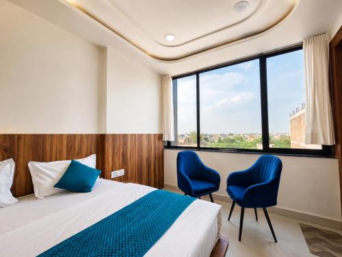 a bedroom with a bed and two blue chairs at Hotel Shree Vrindavan Inn in Vrindāvan