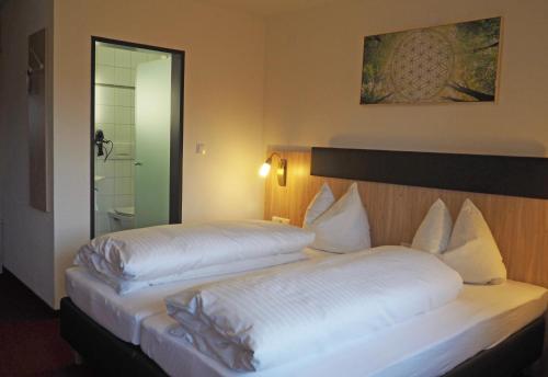 two beds in a hotel room with white sheets at Hotel Restaurant Rössle in Rankweil