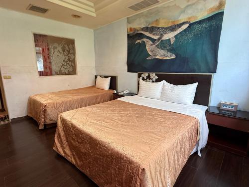 a hotel room with two beds and a painting on the wall at 一品汽車旅館 in Dounan