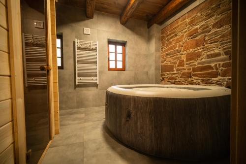 a large wooden tub in a bathroom with a stone wall at Ubytování Pod Mostem in Broumov