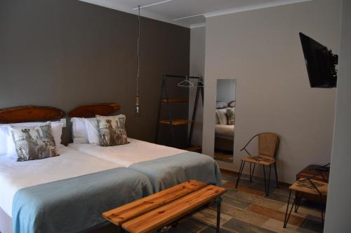 a bedroom with two beds with a bench on it at Quiver Inn Guesthouse in Keetmanshoop
