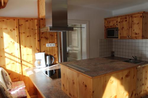 a kitchen with wooden cabinets and a counter top at Schlosswirt Chalets & Apartments in Großkirchheim
