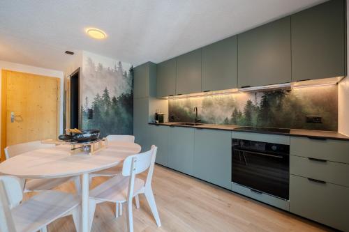 a kitchen with a white table and chairs in a room at Freestyle Alpine Design-Studios - Pool, Parking & Balcony in Center Laax by BlueHills Vacations in Laax
