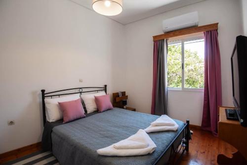 a bedroom with a bed with pink pillows and a window at Chris' Samos Home in Samos