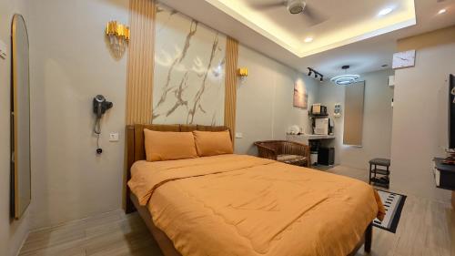 a bedroom with a bed with an orange bedspread at Peacock Studio Tiny House in Kuala Terengganu