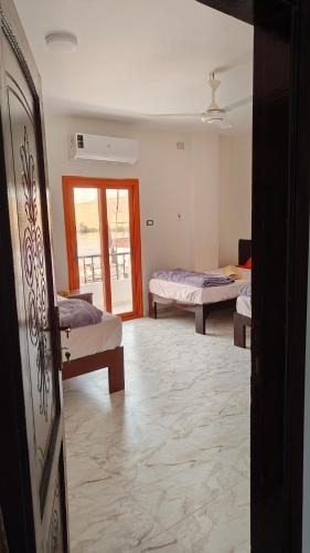 a room with two beds and a door to a balcony at sunset guest house in Aswan