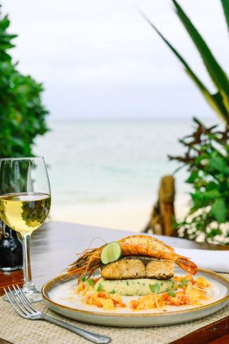a plate of food on a table with a glass of wine at Pongwe Beach Hotel in Pongwe