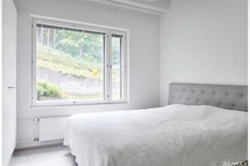 a white bedroom with a bed and a window at Modern two-bedroom apartment in Espoo