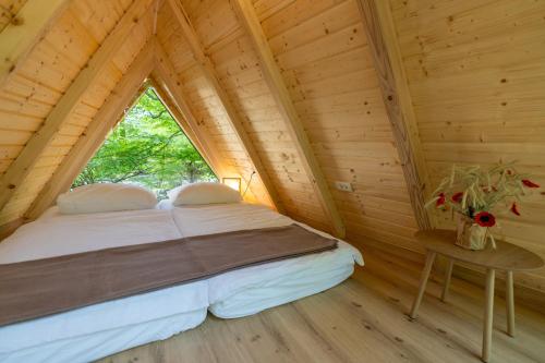 a bed in a log cabin with a window at Youth Hostel Proteus Postojna in Postojna