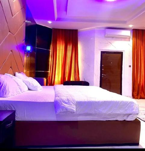 a bedroom with a large white bed with purple lights at Laycon hotel and suites in Ikuata