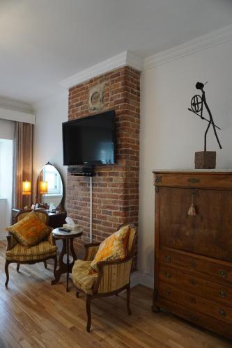 a living room with a tv on a brick wall at Hôtel Marie-Rollet in Quebec City