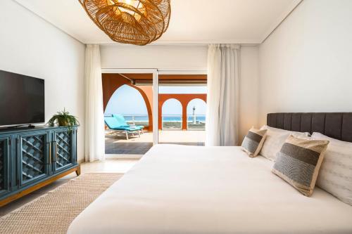 a bedroom with a bed and a television and the ocean at Villa Afreen Playa in Morro del Jable