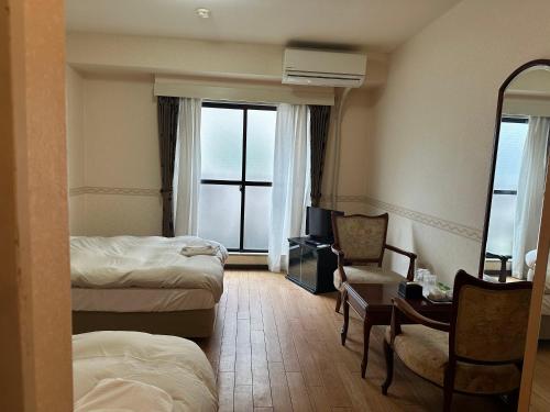 a hotel room with two beds and a chair and a mirror at ACE INN Itabashi in Tokyo