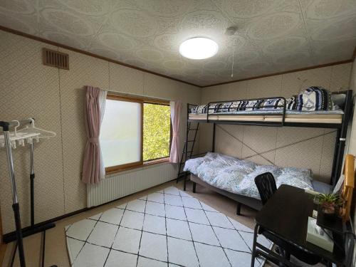 a small room with two bunk beds and a table at EZO HOUSE in Kawayu