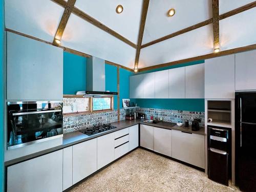 a large kitchen with white cabinets and blue walls at Villa Harimau-Original Joglo style 3B with pool in Gili Trawangan