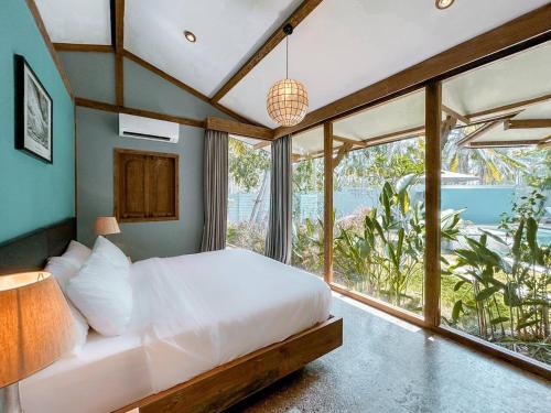 a bedroom with a bed and a large window at Villa Harimau-Original Joglo style 3B with pool in Gili Trawangan