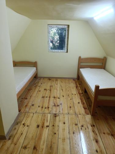 two beds in a room with wooden floors and a window at Sumski raj Gornje podunavlje in Sombor