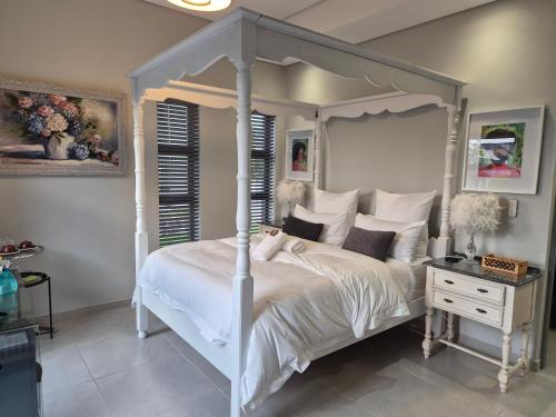 a bedroom with a white canopy bed and a table at 8 Guildford in George