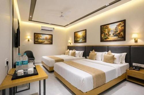 a hotel room with two beds and a television at Paradise Grand Hotel Delhi igi Airport in Etāwah