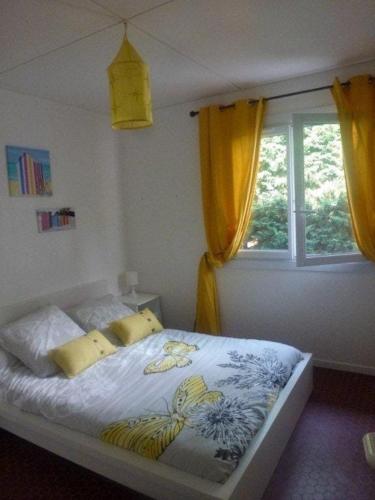 a bedroom with a bed with yellow curtains and a window at Maison huit places Piscine tennis Lacanau plage in Lacanau