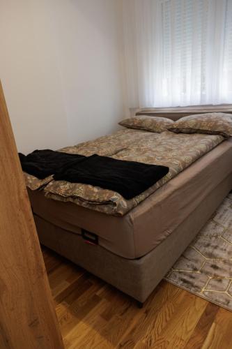 a bed sitting in a room next to a wall at Apartmani Savić expres Laktasi in Laktaši