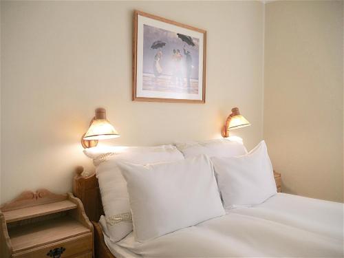 a bedroom with a bed with white pillows and two lamps at Rondane Høyfjellshotell in Mysusæter