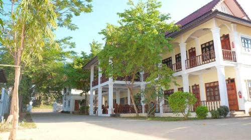 a white building with a balcony on a street at Dokban Hotel in Luang Prabang