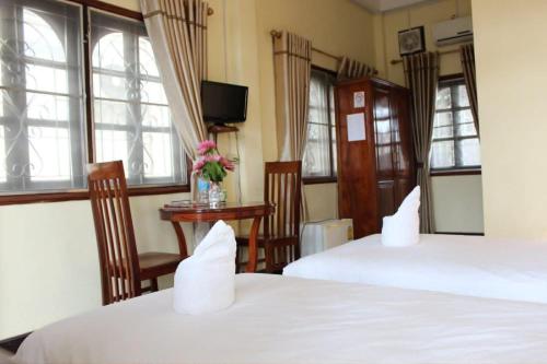 a hotel room with two beds and a tv at Dokban Hotel in Luang Prabang