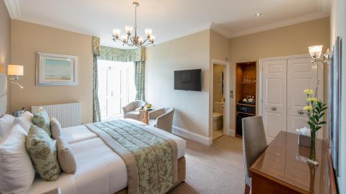 a hotel room with a bed and a desk and a table at The Belmont Hotel in Sidmouth