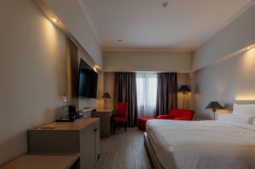 a hotel room with a bed and a desk and chairs at Azana Oasis Hotel Aceh in Luengbata