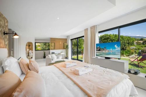 a white bedroom with a large bed and a large window at Villa Romy, a World apart in Roquebrune-Cap-Martin