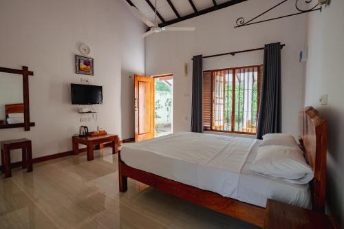 a bedroom with a large bed and a television at Mountain Edge By Yala Odyssey in Kataragama