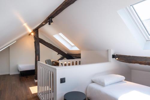 a small attic bedroom with a bed and skylights at Hôtel des Métallos in Paris