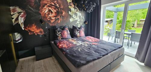 a bedroom with a bed with flowers on the wall at Gartenbungalow Rhönherz in Hilders