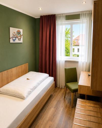 a bedroom with a bed and a chair and a window at Burggasthof Weißenstein in Regen