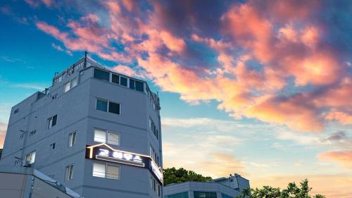 a tall building with a cloudy sky in the background at Busan Go House Pension in Busan