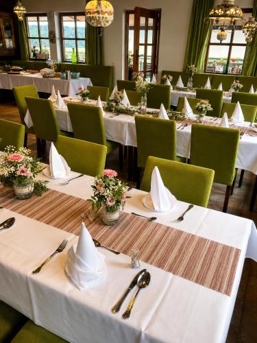 a row of tables in a restaurant with white tables and green chairs at Burggasthof Weißenstein in Regen