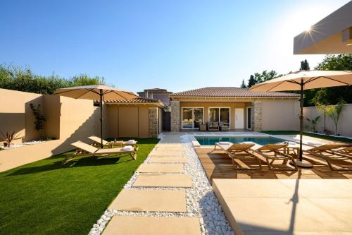 a backyard with a pool and patio furniture and umbrellas at Villa Idola Dassia Corfu in Dassia