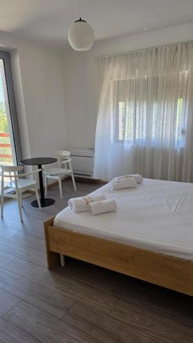 a bedroom with a bed with white sheets and a window at Villa Kroi i Vashes in Peqin