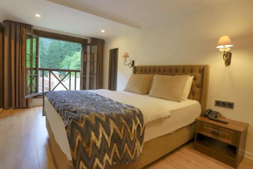 a bedroom with a large bed and a balcony at İSKALİTA Otel in Altındere