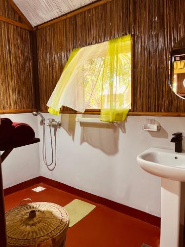 a bathroom with a sink and a yellow window at Mahanoro Hotel & Restaurant in Sainte Marie