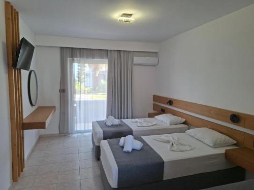 a hotel room with two beds and a television at Evripides Village in Kardamaina